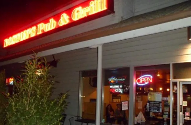 Exterior of Boston's Pub & Grill at night with neon signs and open entrance