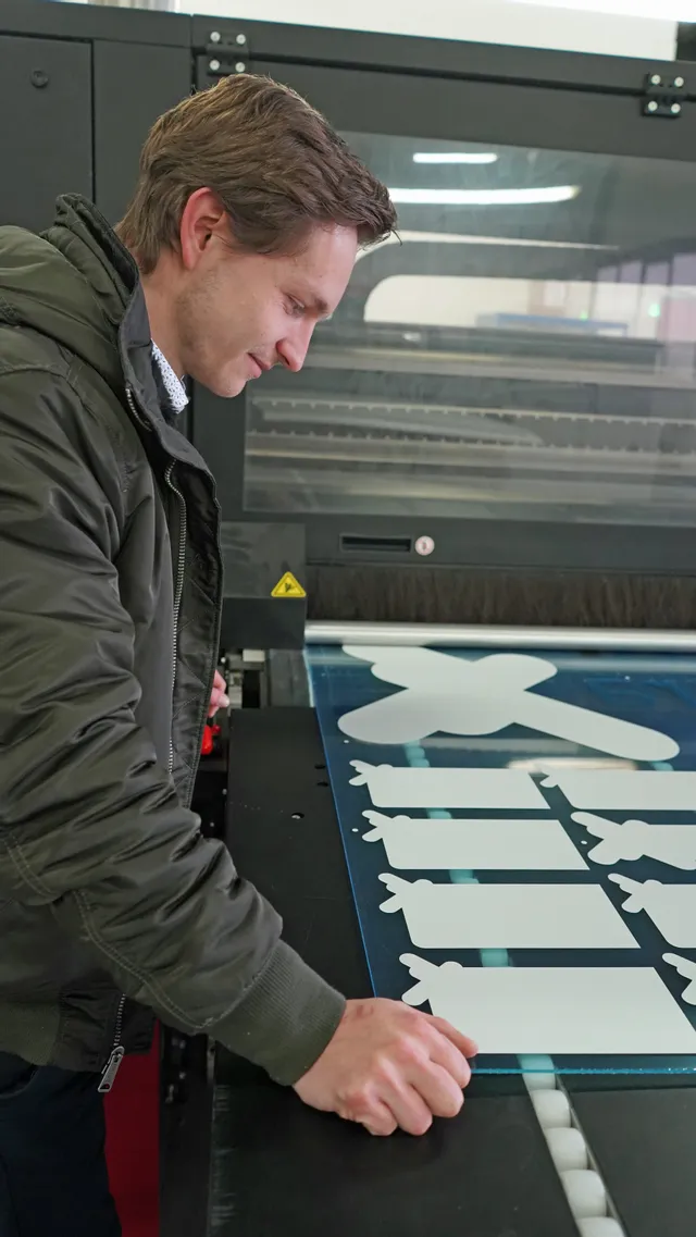 Operario retirando formas acrílicas cortadas de la cortadora láser Trotec en el taller