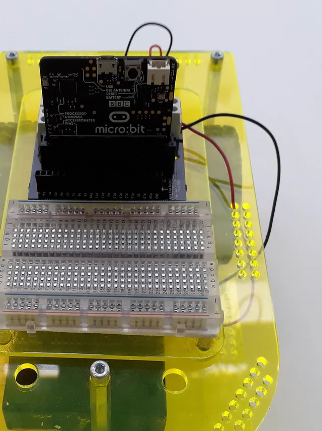 BBC micro:bit connected to breadboard on yellow acrylic base for electronics prototyping