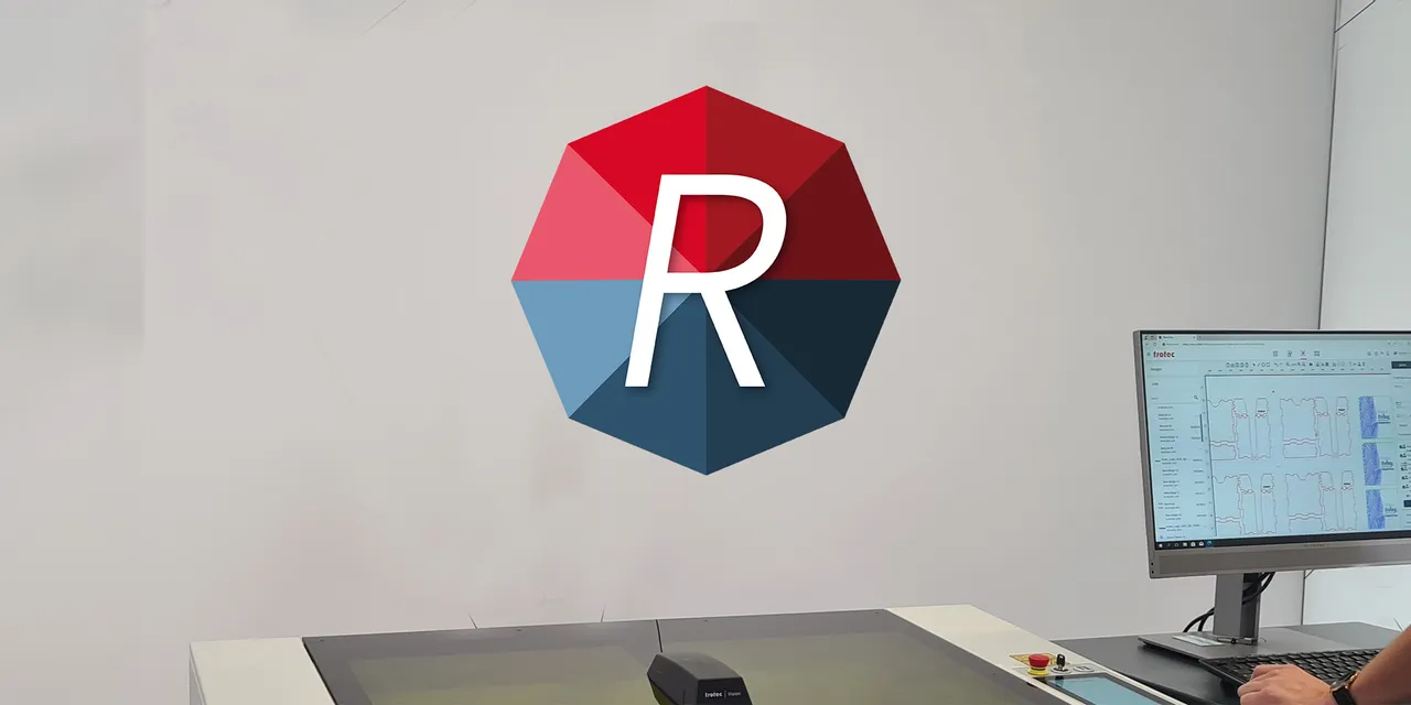 User operating Trotec Ruby software on screen next to laser cutter from Speedy series