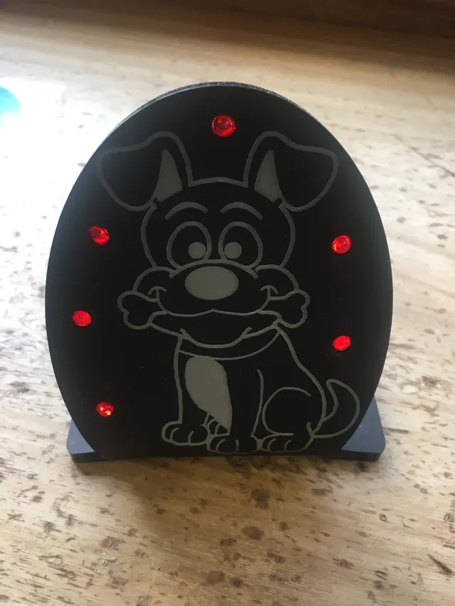 Laser-engraved black acrylic dog design with red LED lights created using Trotec laser cutter