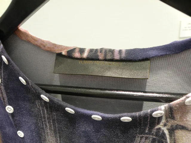 Nahaufnahme eines Designerkleidungsstücks mit sichtbarem Etikett und Knopfdetails auf einem Kleiderbügel