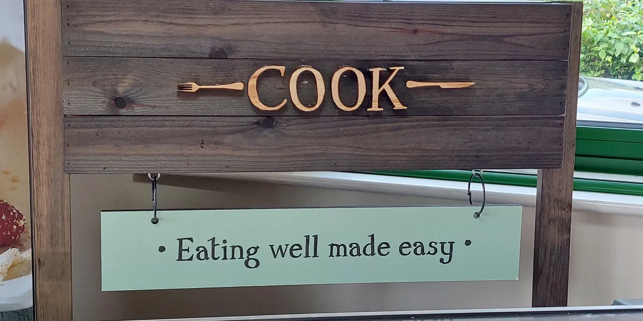Wooden CO₂ laser-engraved COOK sign with tagline 'Eating well made easy', likely produced using Trotec laser cutter