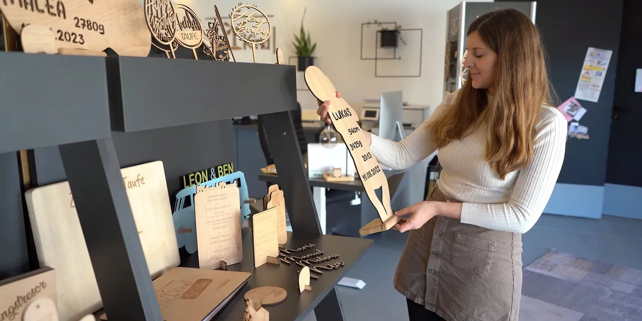 Woman displaying wooden signs created with Trotec CO₂ laser engraving machine
