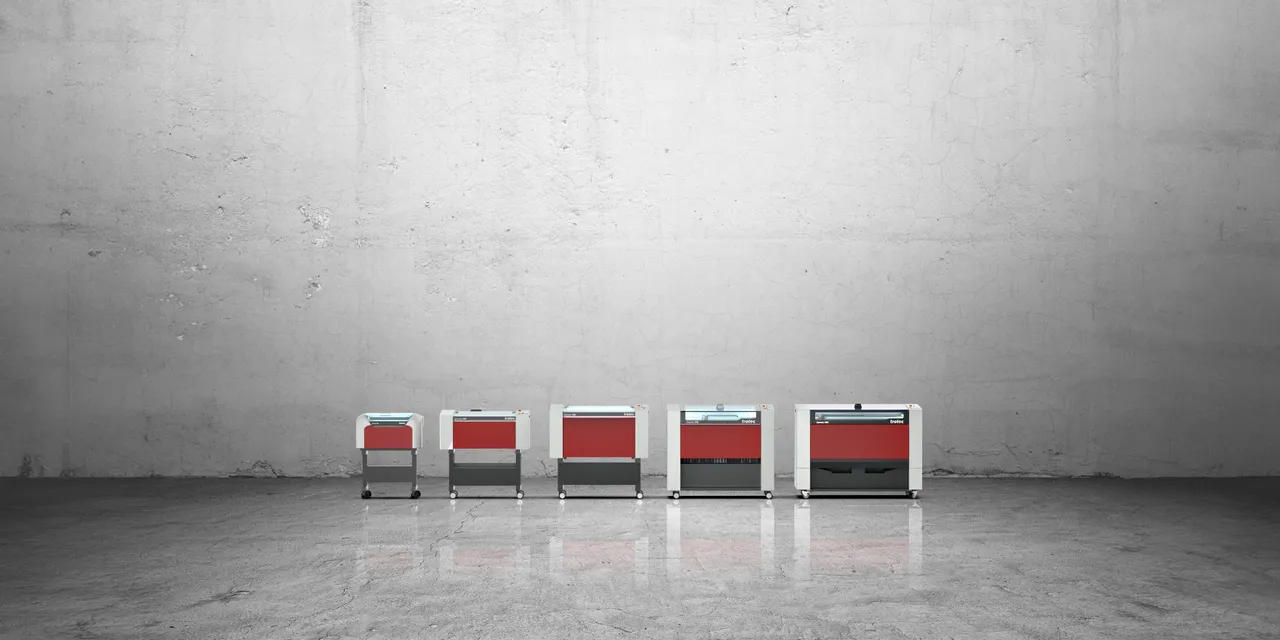 Gamme complète de machines de gravure laser CO₂ de la série Speedy de Trotec sur fond de béton.