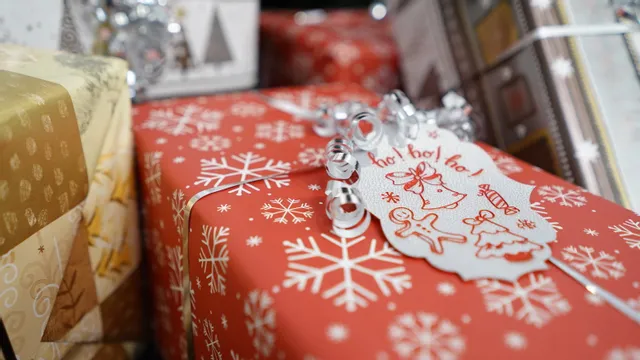 Mit dem Laserschneider von Trotec CO₂ gravierter Weihnachtsgeschenkanhänger auf rotem Schneeflocken-Geschenkpapier