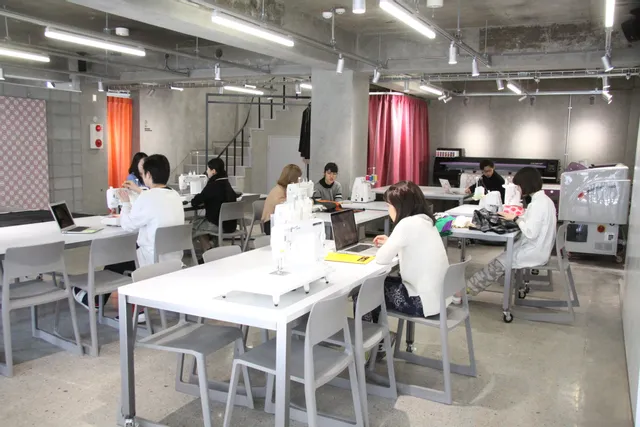 Students working on laptops and textile projects beside sewing machines in a modern makerspace