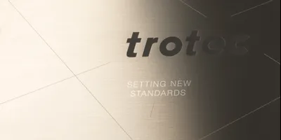 Trotec laser-engraved metal sign with brand logo and slogan 'Setting new standards'