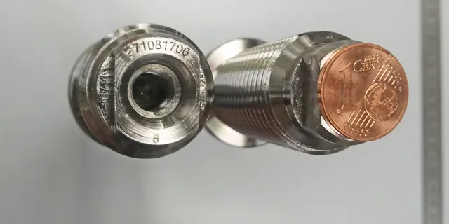 Metal sensor engraved with serial number using Trotec laser marking technology beside 1 cent coin for scale