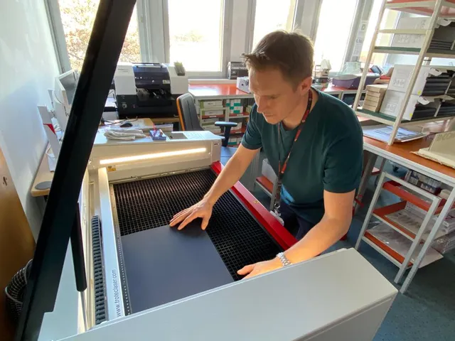 Operator placing material inside Trotec Speedy series CO₂ laser cutter for engraving