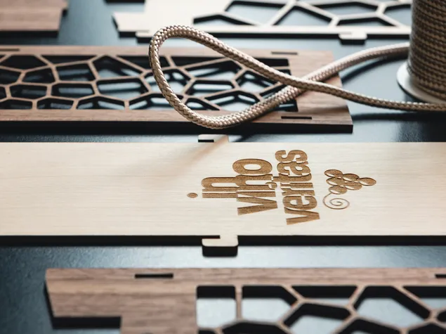 트로텍 CO₂ 레이저 커터를 사용하여 '인 비노 베리타스'가 새겨진 레이저 커팅 목재 부품