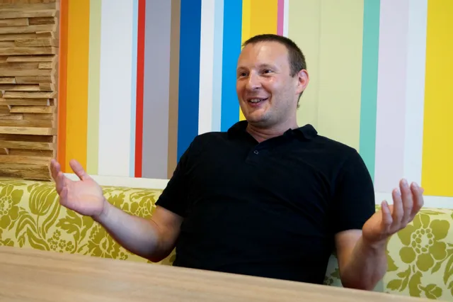 Man smiling and gesturing during indoor conversation in modern, colorful office space