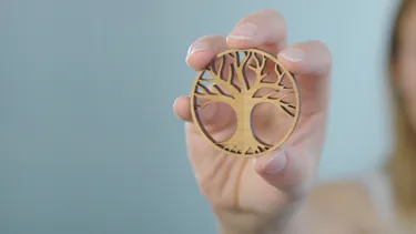 Hand holding laser-cut wooden tree design made with Trotec CO₂ laser cutter