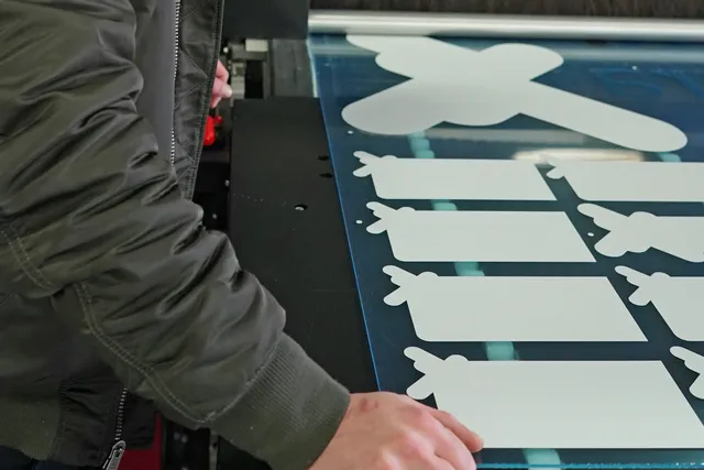 Operator removing cut acrylic shapes from Trotec laser cutter in workshop