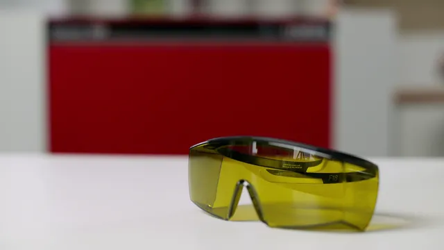 Laser safety glasses placed on table in front of red Trotec laser cutter