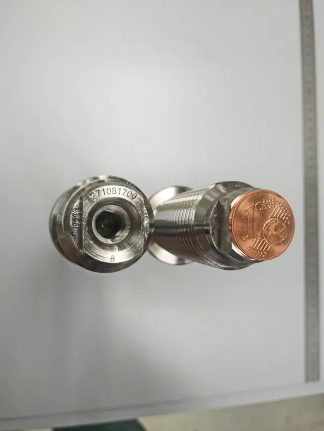 Mit der Gravurtechnologie von Trotec Laser gravierter Metallsensor mit Seriennummer neben einer 1-Cent-Münze als Maßstab