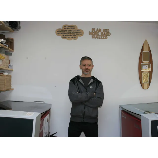Man standing between two Trotec Speedy 300 laser cutters in a workshop with engraved wall art