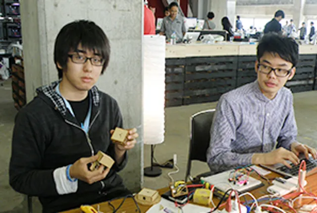 レーザー彫刻機プロジェクトのためか、電子機器と木製部品を組み立てる2人の製作者。