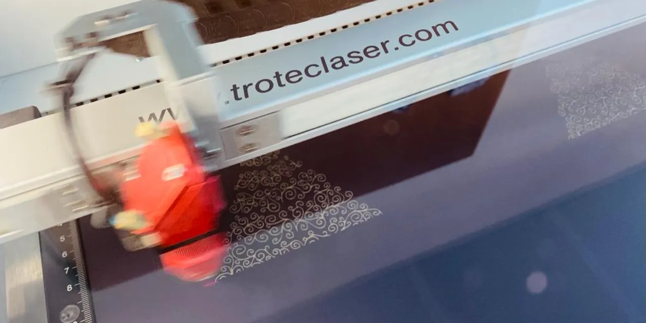Trotec laser cutter engraving intricate pattern on dark acrylic sheet