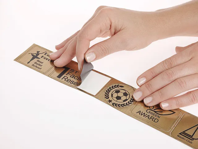 Les mains en train de décoller le ruban de masquage des récompenses en acrylique gravées au laser et réalisées avec la machine de découpe laser.