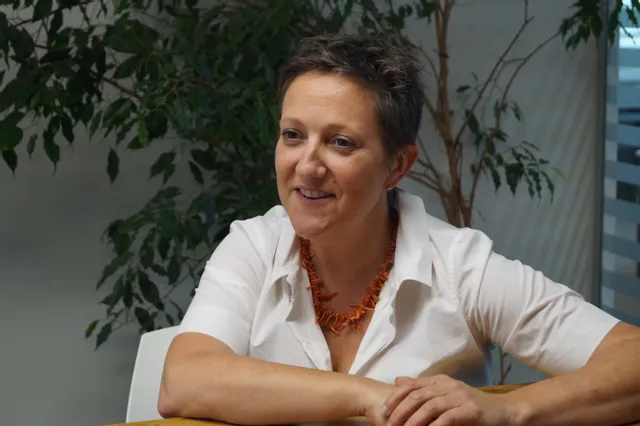 Lächelnde Frau in weißem Hemd während einer Bürobesprechung mit Pflanzen im Hintergrund