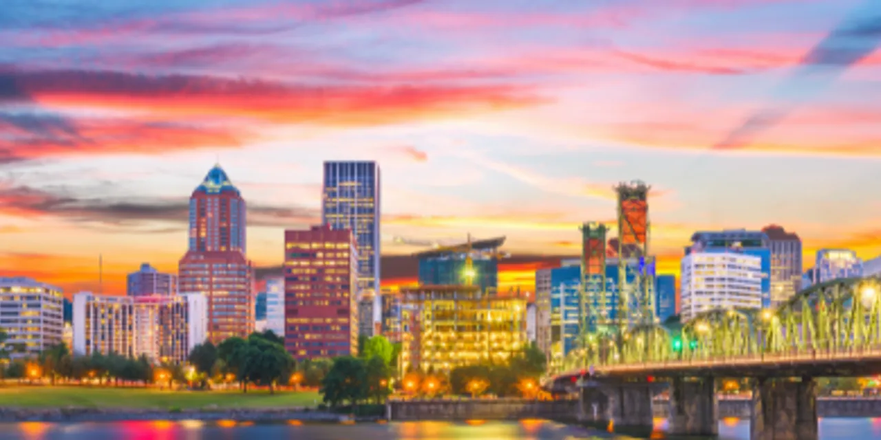 Downtown Portland skyline at sunset with city lights and bridge reflecting on the Willamette River