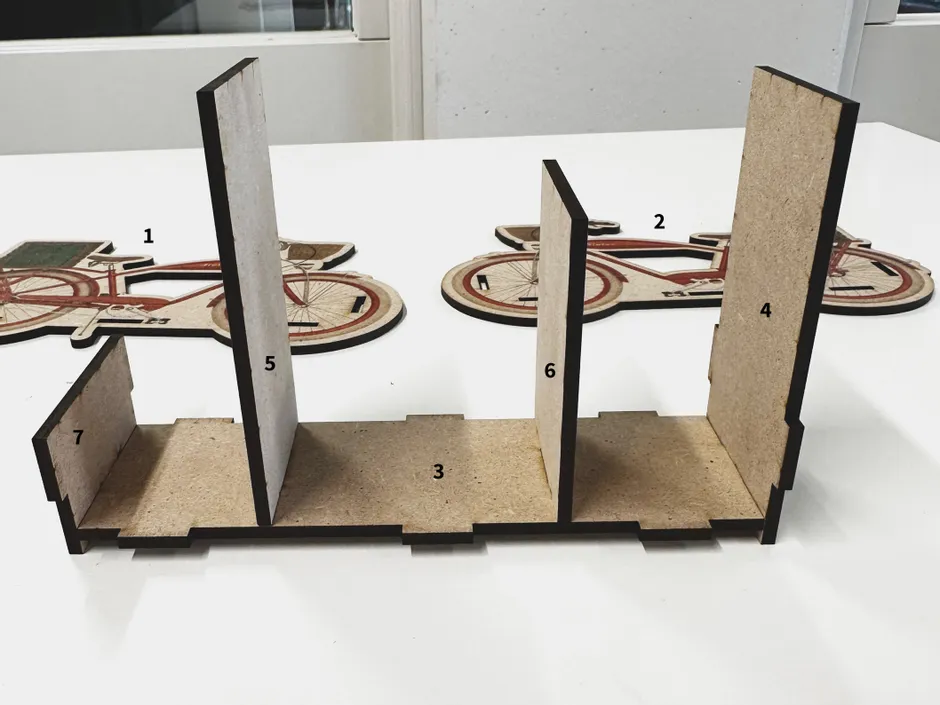 Parti del puzzle della bicicletta in MDF tagliate al laser e base di montaggio realizzata con la taglierina laser Trotec CO₂.