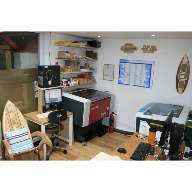 Trotec Speedy 300 CO₂ laser engraver in a workspace with Ruby software and materials on shelves