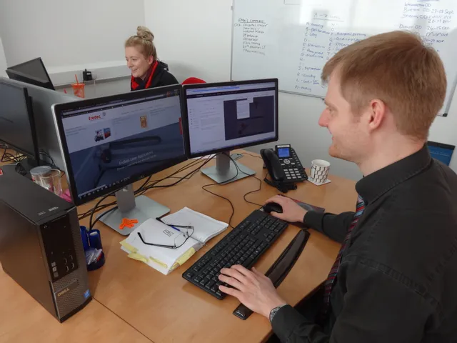 Kantoorpersoneel bekijkt Trotec lasersnijder en Ruby software op twee monitoren