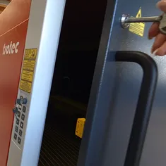 Operatør låser Trotec Speedy serie CO₂-laserskærer op med sikkerhedsnøgle