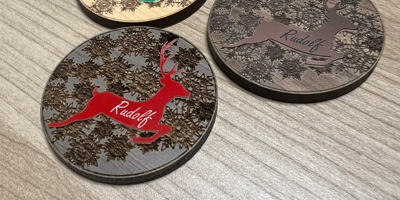 Laser-engraved wooden ornaments with colored reindeer designs made using Trotec CO₂ laser cutter