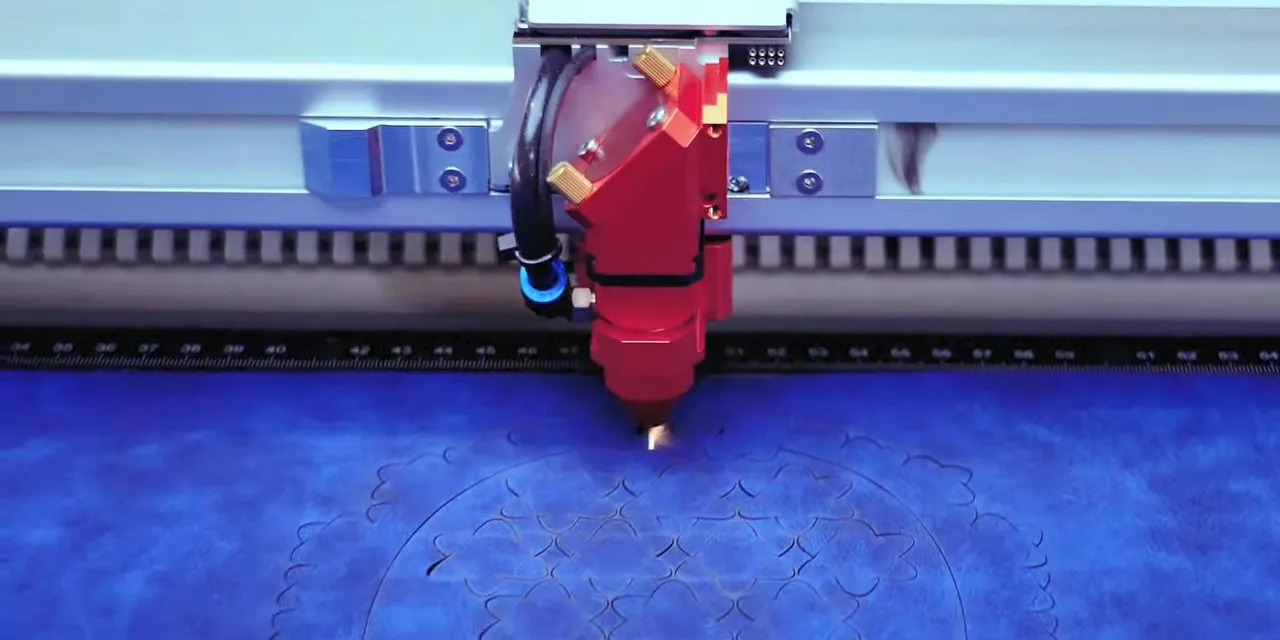 Cortador a laser Trotec gravando um intrincado padrão floral em material azul com tecnologia CO₂