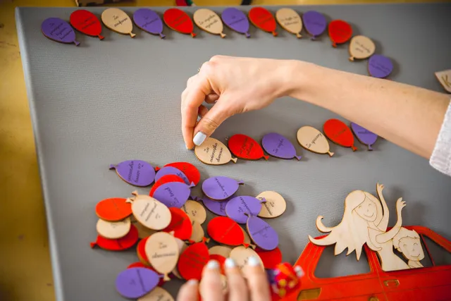 Laser-cut wooden balloons with engraved text arranged on canvas using Trotec CO₂ laser technology