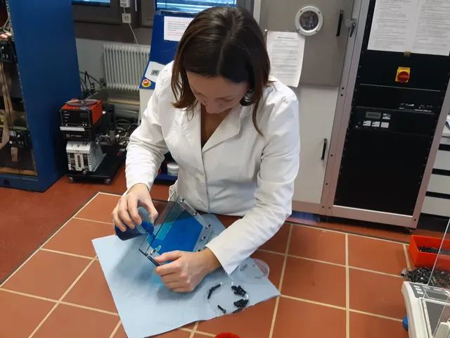 Wissenschaftlerin im Laborkittel gießt blaue Flüssigkeit in eine Acrylform für einen Test zum Lasergravieren