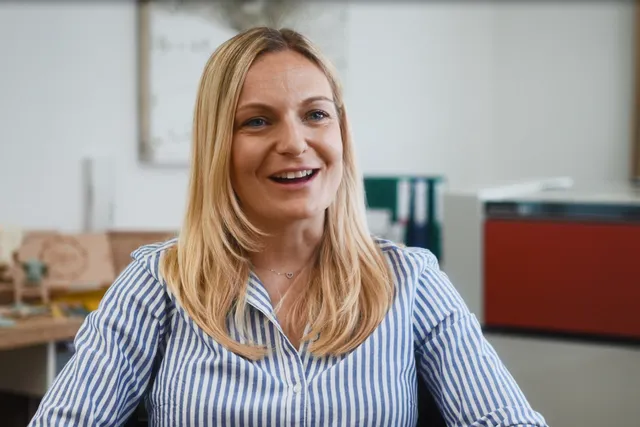 トロテック・レーザーカッターSpeedyシリーズを背景にオフィスに座る女性。