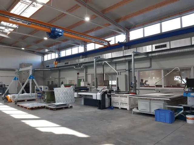 Industrielt arbejdsområde med Trotec-laserskæremaskine og materialehåndteringsudstyr