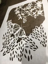 白い材料にトロテック・CO₂レーザーカッターでカットされた複雑な蝶と花のステンシル