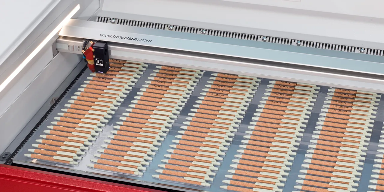 Laser Trotec Speedy mengukir beberapa pena kayu di dalam pemotong laser CO₂