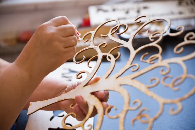 Ręczne wykończenie wycinanego laserowo wzoru drewnianego drzewa stworzonego za pomocą wycinarki laserowej Trotec CO₂.