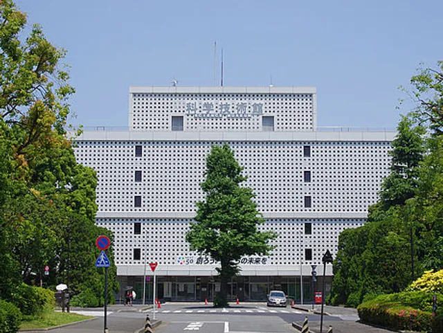 シンメトリーな格子状のファサードと中央の並木道のエントランスを持つ近代的な複数階の庁舎