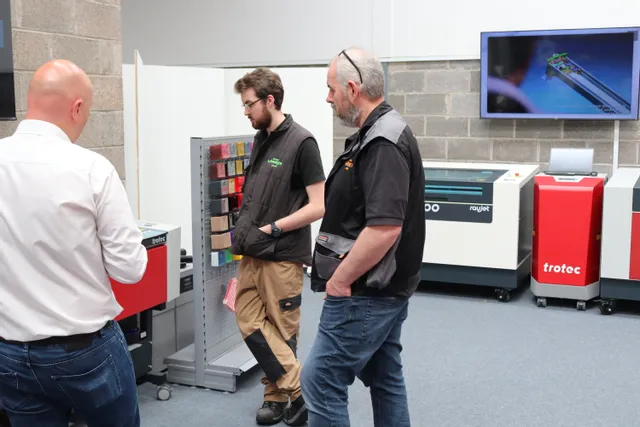 Technicians discuss Trotec Rayjet laser cutter and engraving machine in demo room