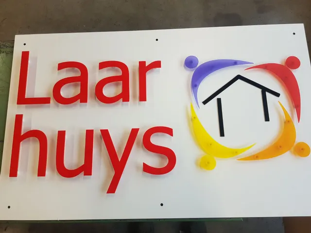 Laser-cut acrylic sign with red text and colorful logo, made using Trotec laser cutter