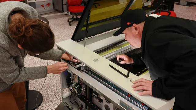 Technicians performing maintenance on Trotec Speedy series laser engraving machine