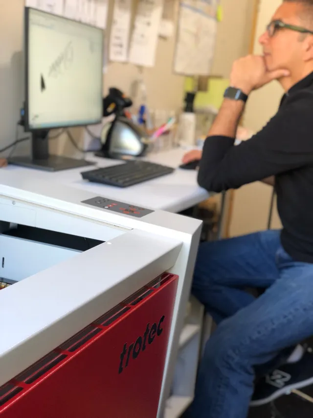Operator working with Trotec Speedy laser cutter and Ruby software on desktop