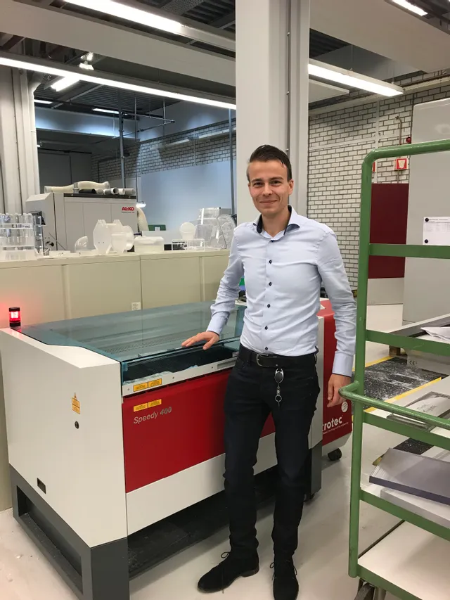 Man standing beside Trotec Speedy 400 CO₂ laser cutter in modern workshop