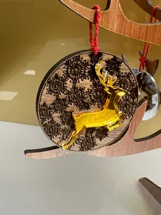 Ornement en bois découpé au laser avec des flocons de neige gravés et des rennes en acrylique jaune, réalisé à l'aide de la machine de découpe laser Trotec.