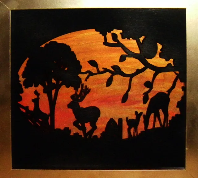 Laser-cut wood art of deer in forest at sunset made with Trotec Speedy series laser engraver