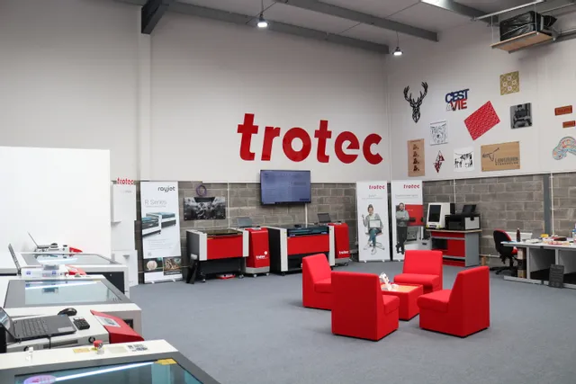 Trotec showroom displaying Speedy series laser cutters, R Series machines, and Ruby software banners