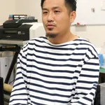 トロテック・レーザー彫刻機を背景にオフィスで話す男性。