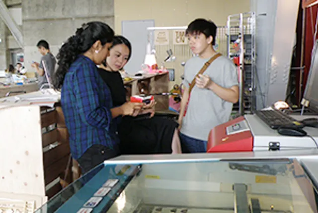 メーカースペースでレーザーカッターSpeedyシリーズを囲んでプロジェクトについて話し合うグループ